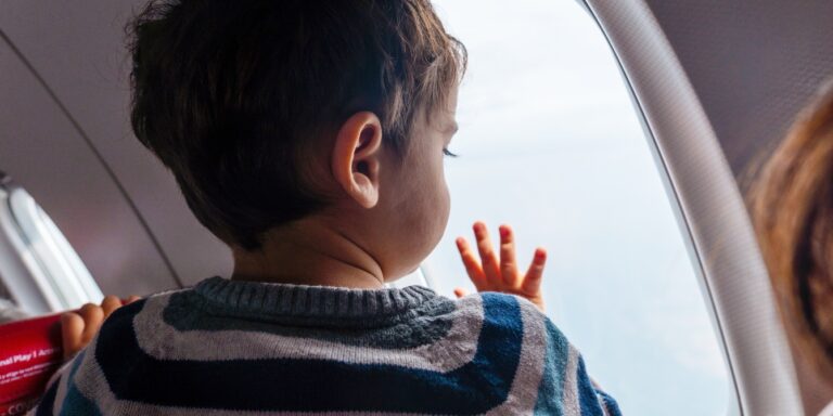 toddler boy looking out airplane window