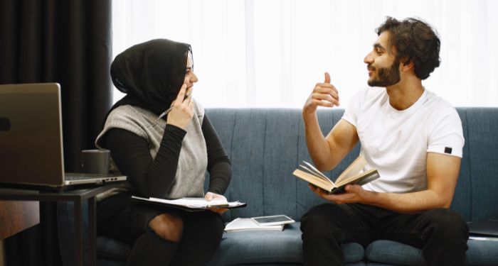 two Middle Eastern people with light tan skin a man and a woman sitting and discussing a book.jpg.op